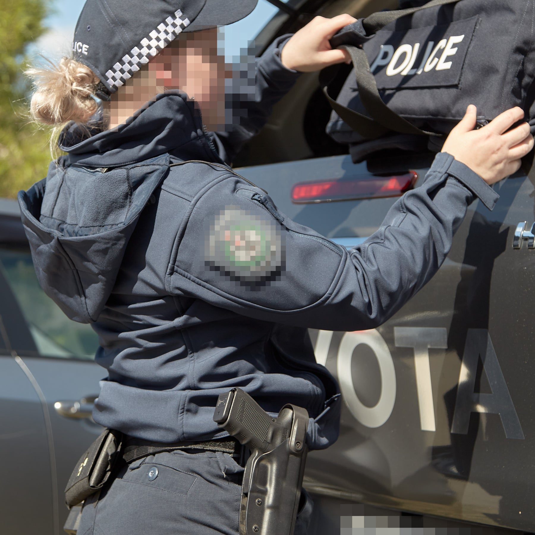 Australian police member wearing Platatac operational outerwear beside a police vehicle